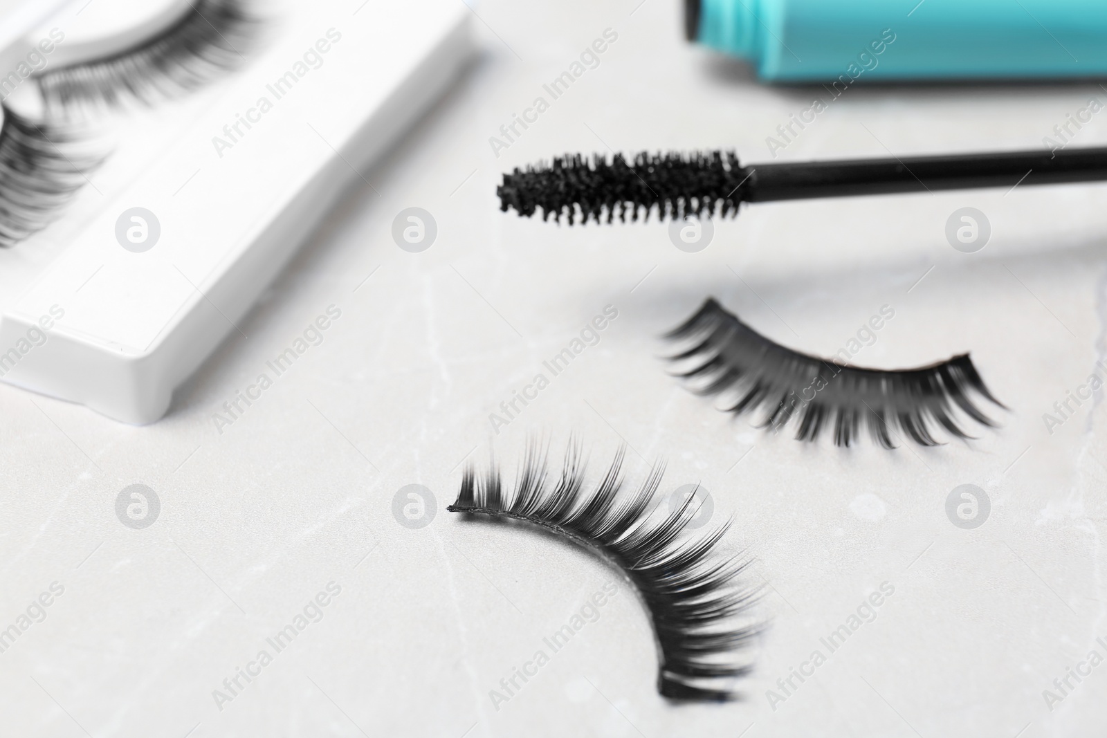 Photo of Mascara brush and false eyelashes on table, closeup