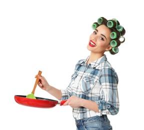 Photo of Funny young housewife with hair rollers holding spoon and frying pan on white background