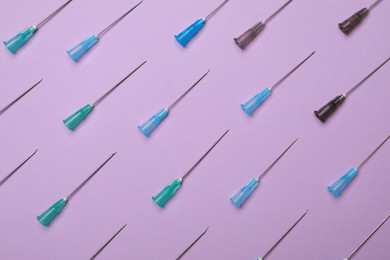 Disposable syringe needles on violet background, flat lay