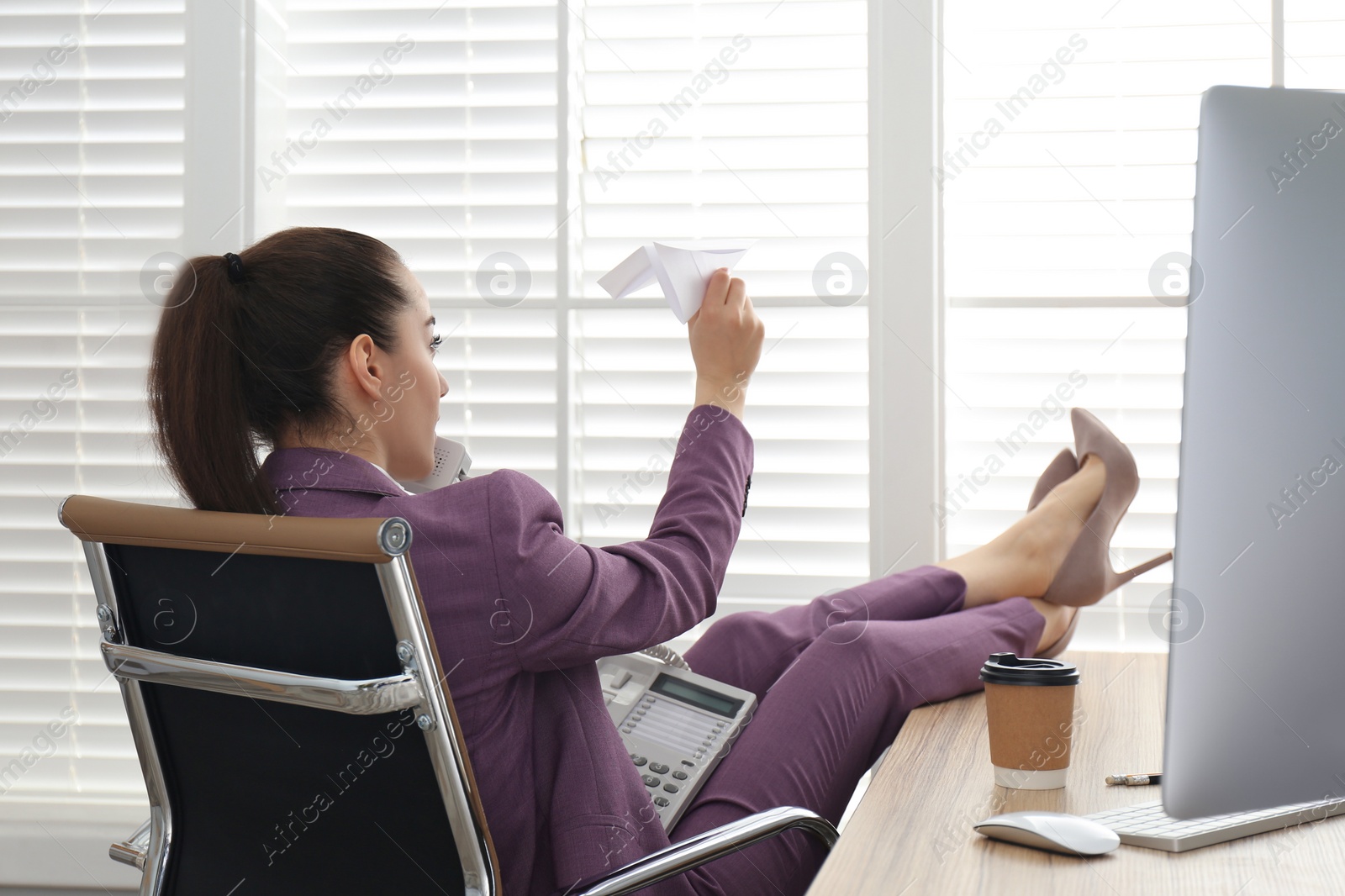 Photo of Lazy employee playing with paper plane in office