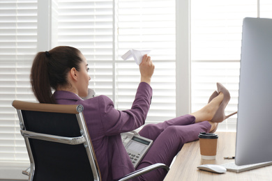Photo of Lazy employee playing with paper plane in office