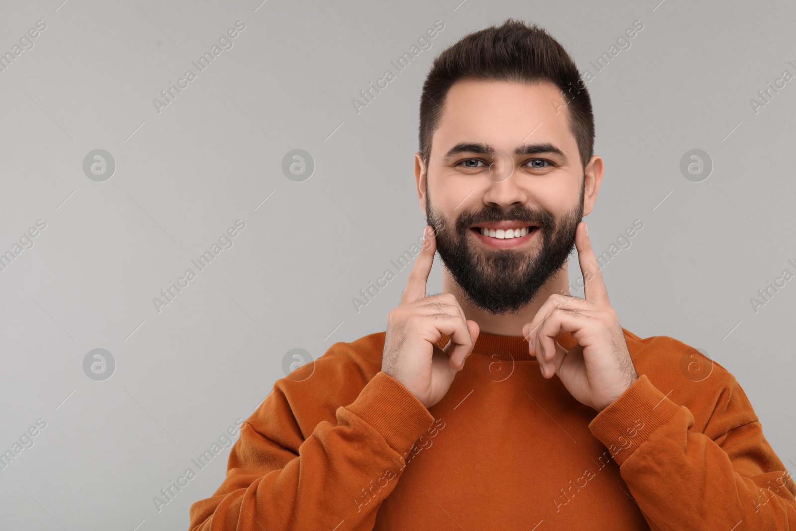 Photo of Man showing his clean teeth and smiling on gray background, space for text