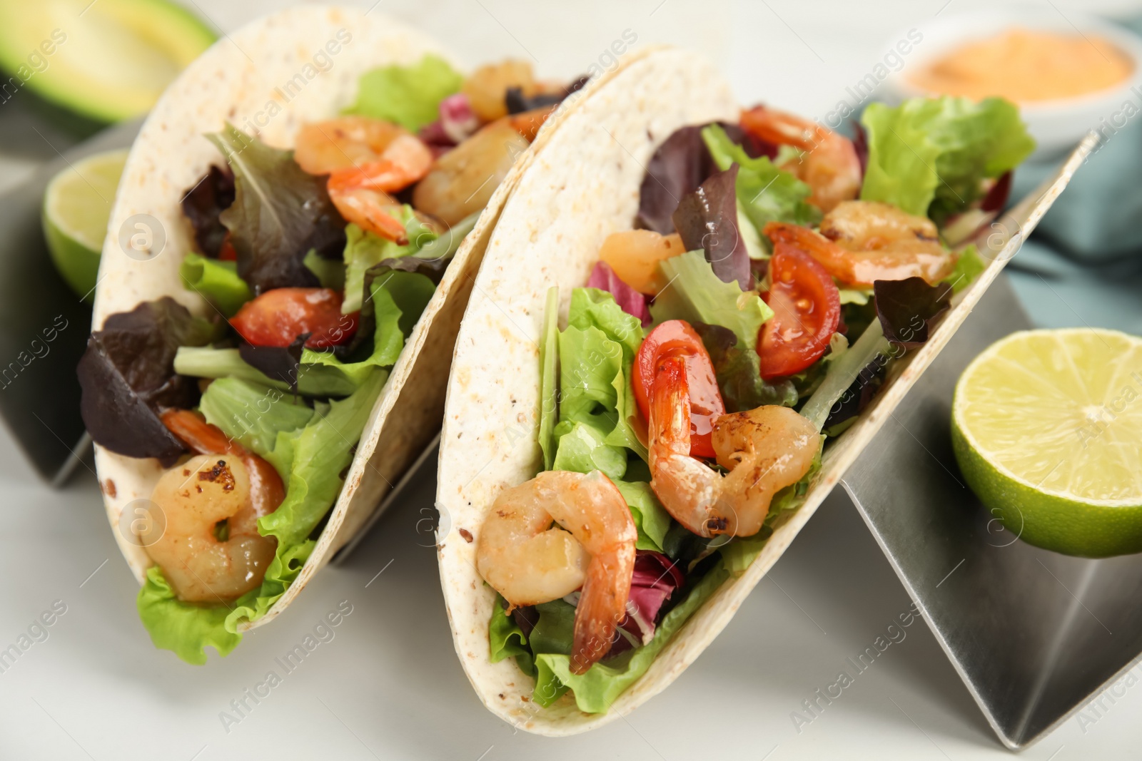 Photo of Delicious tacos with shrimps and lime on white table, closeup