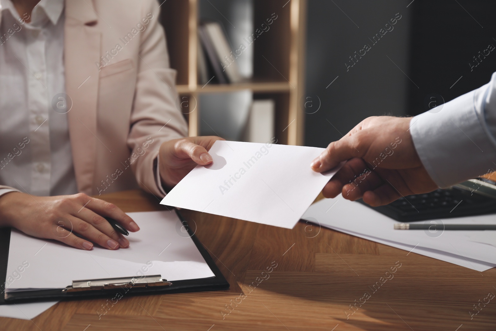 Photo of Employee giving resignation letter to boss in office, closeup