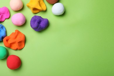 Photo of Colorful plasticine on green background, flat lay. Space for text