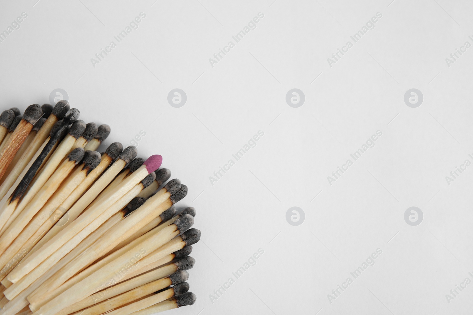 Photo of Heap of burnt matches and whole one on white background, flat lay. Space for text