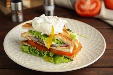 Photo of Tasty sandwich with poached egg on wooden table