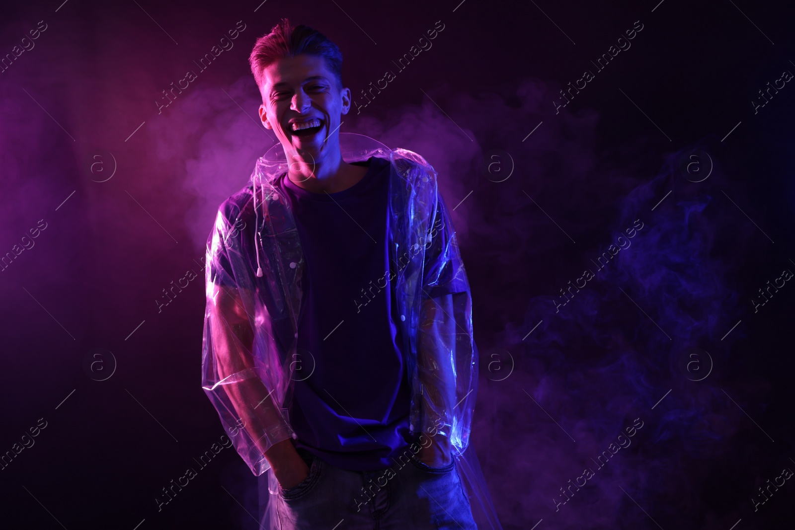 Photo of Young man wearing clear coat in neon lights with smoke effect. Space for text