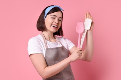 Photo of Happy confectioner with spatulas on pink background