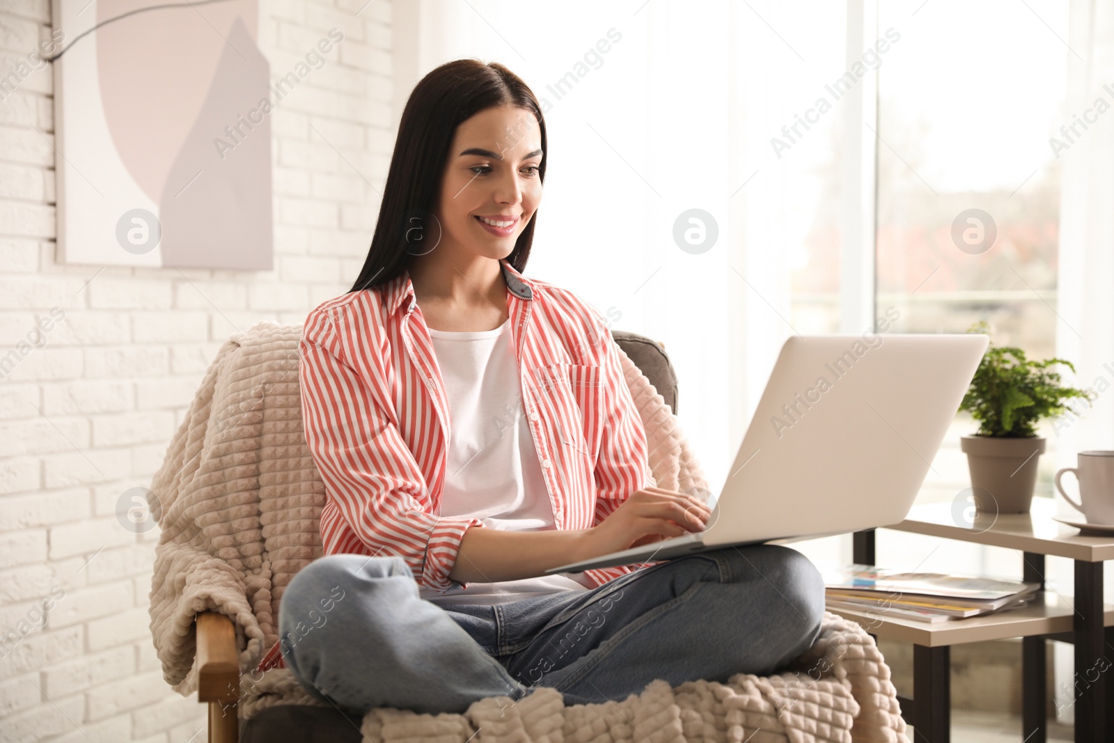 Photo of Beautiful young woman using laptop at home