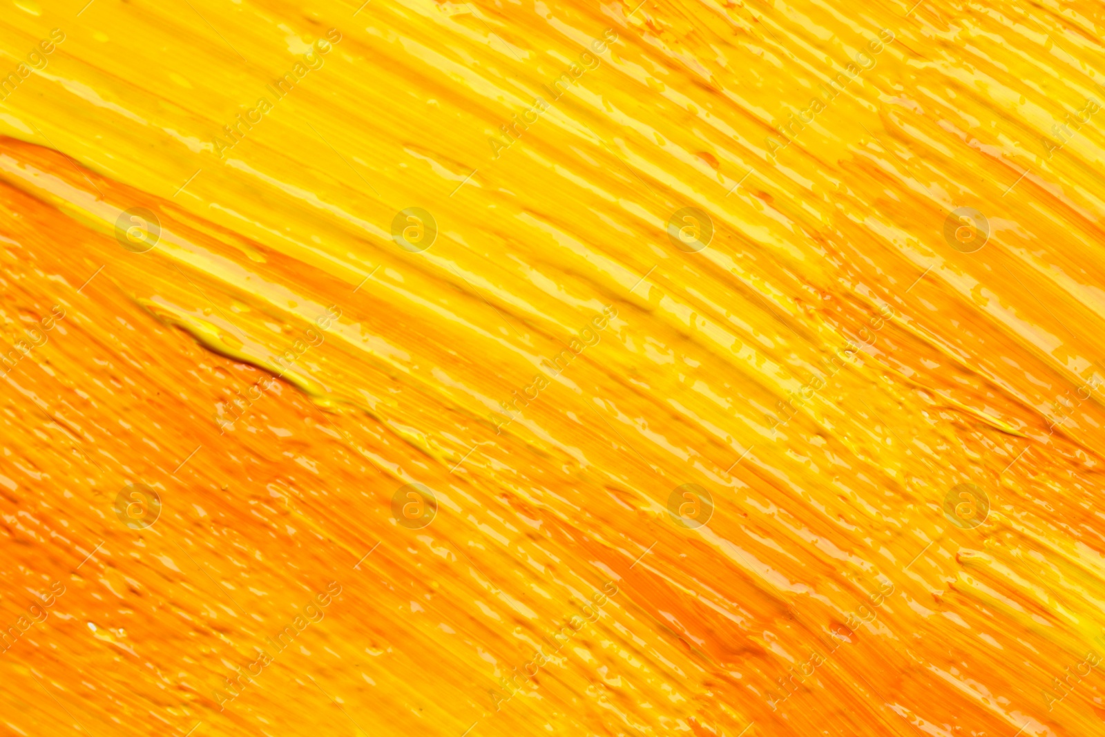 Photo of Beautiful strokes of yellow and orange oil paints as background, closeup