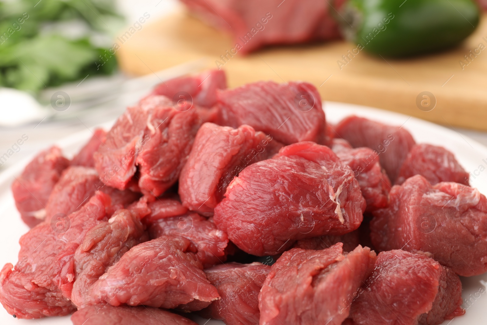 Photo of Plate with pieces of raw beef meat on table, closeup