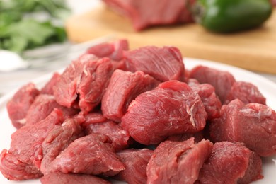 Photo of Plate with pieces of raw beef meat on table, closeup