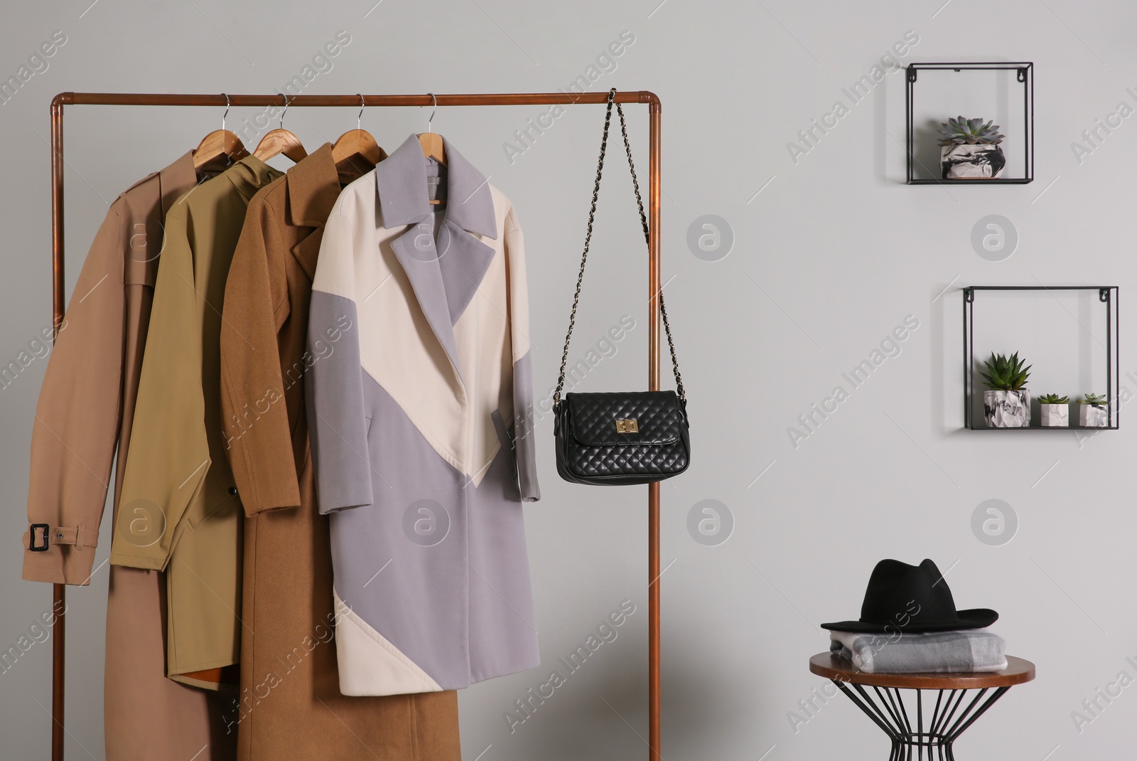 Photo of Different warm coats on rack in stylish room interior