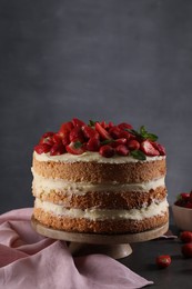Photo of Tasty cake with fresh strawberries and mint on table against dark gray background