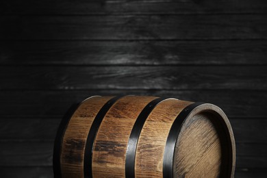 Photo of One wooden barrel near dark wall, closeup. Space for text