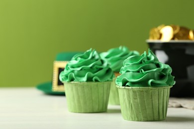 Photo of St. Patrick's day party. Tasty cupcakes with green cream on white table. Space for text