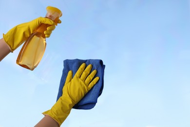 Photo of Woman cleaning window glass with rag and detergent, closeup. Space for text