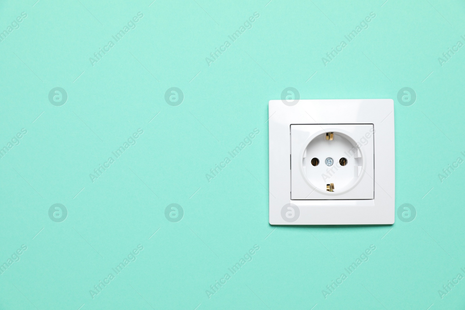 Photo of Power socket on turquoise wall, space for text. Electrical supply