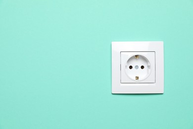 Power socket on turquoise wall, space for text. Electrical supply