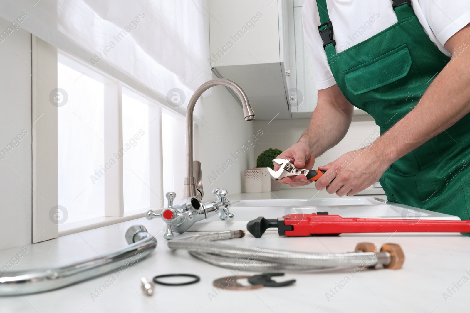 Photo of Professional plumber fixing water tap in kitchen, closeup