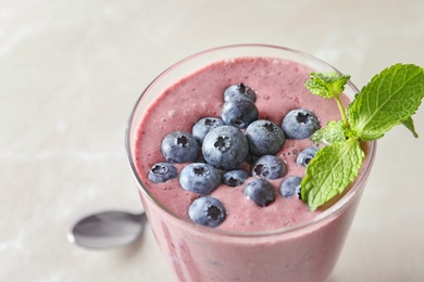 Photo of Glass with blueberry smoothie on light background, closeup