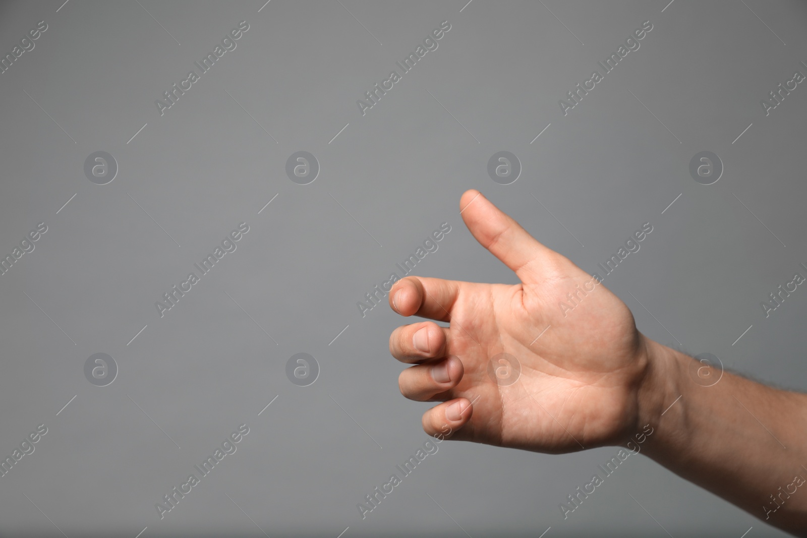 Photo of Man holding something in hand on grey background, closeup. Space for text