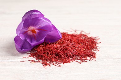 Photo of Dried saffron and crocus flower on white wooden table, closeup