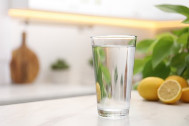 Glass with clear water on white table in kitchen, space for text