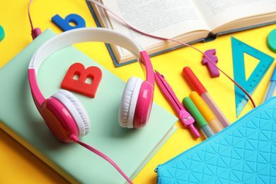 Photo of Books, headphones and stationery on yellow background