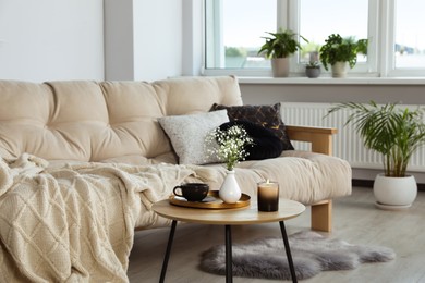 Photo of Sofa and round wooden table with decorative elements in living room. Interior design