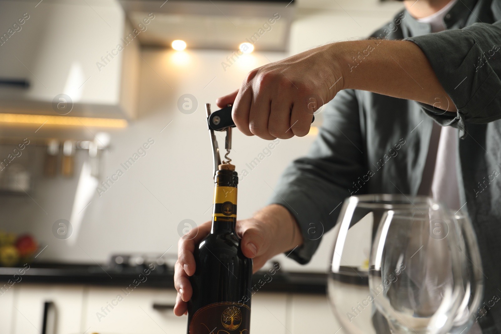 Photo of Man opening wine bottle with corkscrew indoors, closeup. Space for text