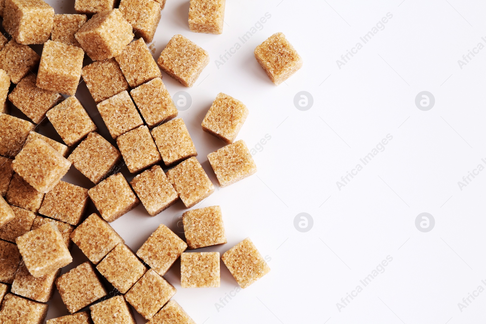 Photo of Brown sugar cubes on white background, top view. Space for text