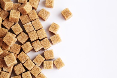 Photo of Brown sugar cubes on white background, top view. Space for text