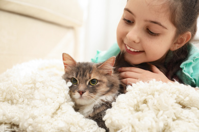 Cute little girl with cat lying at home. First pet