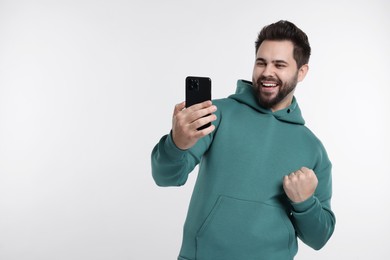 Happy young man using smartphone on white background, space for text