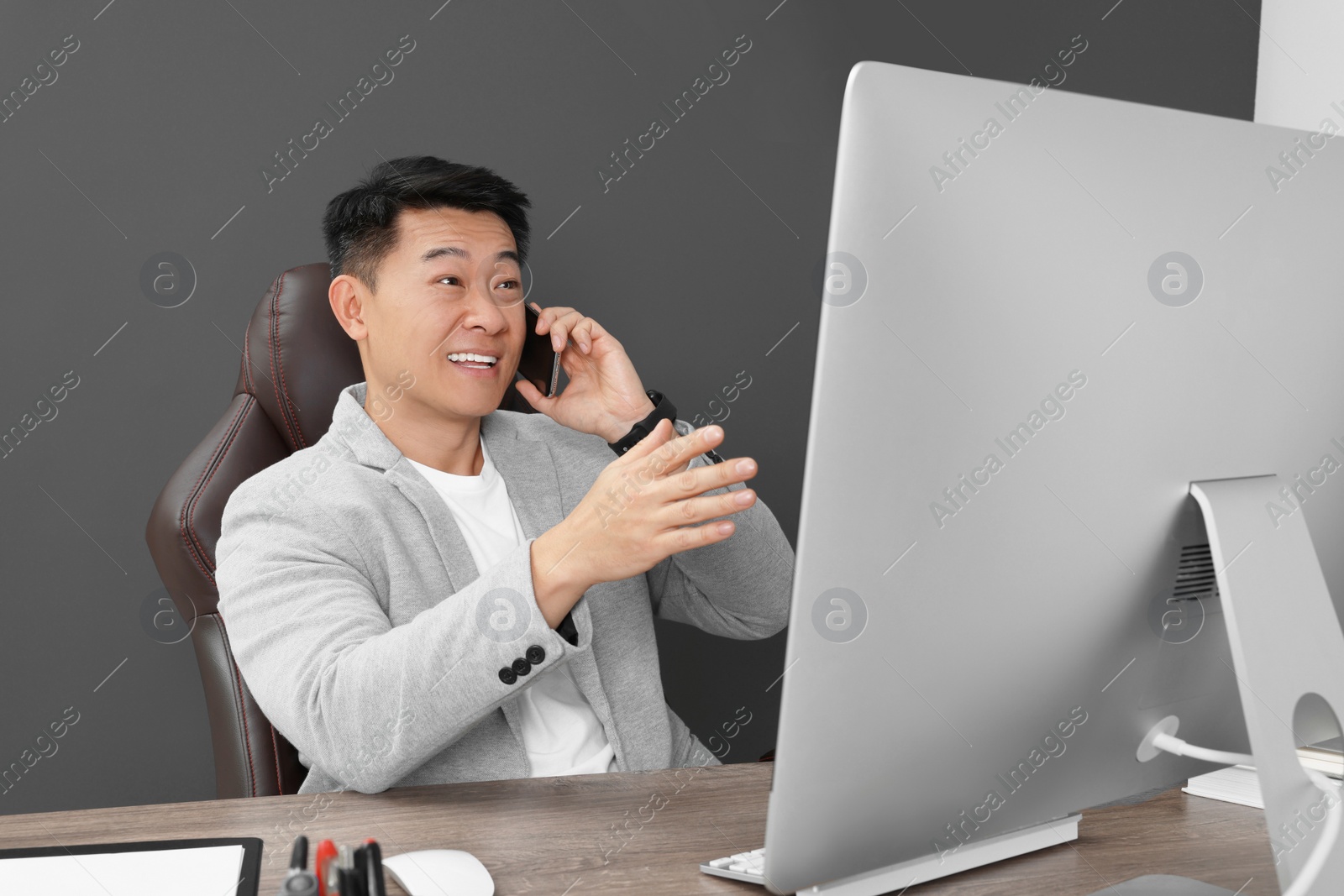 Photo of Happy boss talking on phone in his office