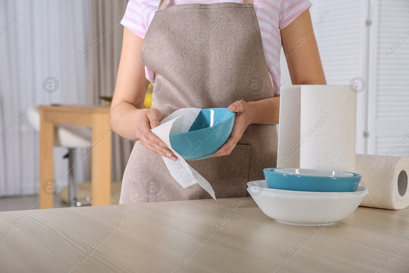 Photo of Woman wiping bowl with paper towel in kitchen, closeup