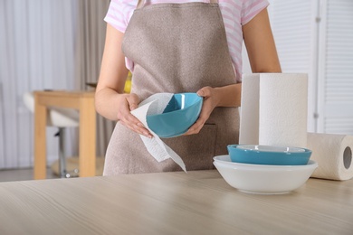 Woman wiping bowl with paper towel in kitchen, closeup