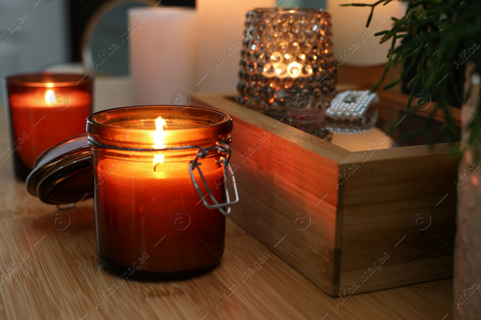 Photo of Lit candles on wooden dressing table indoors