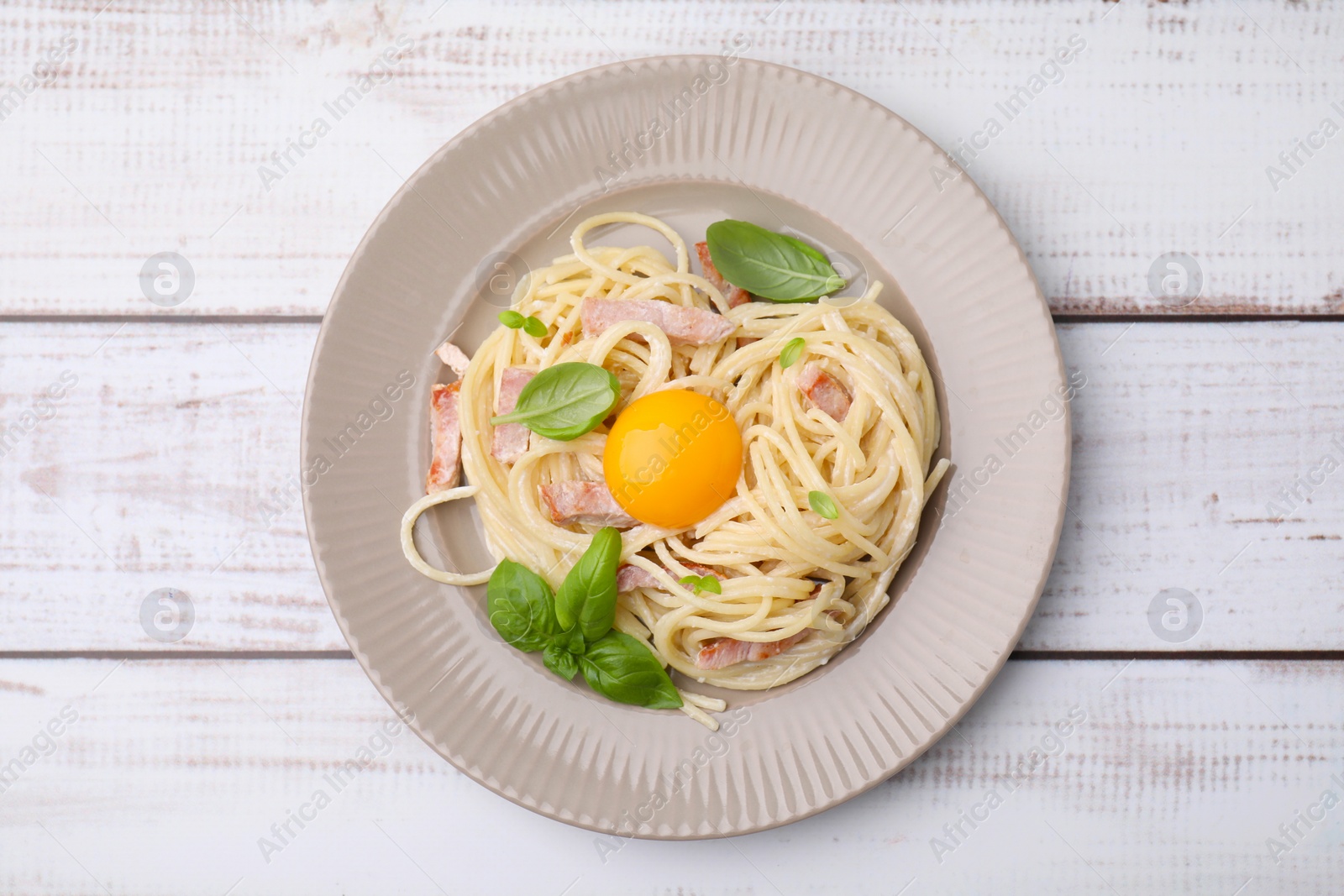 Photo of Delicious pasta Carbonara with egg yolk on white wooden table, top view