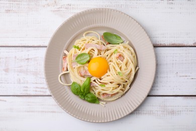 Delicious pasta Carbonara with egg yolk on white wooden table, top view