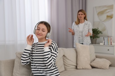 Photo of Teenage daughter with headphones ignoring her mother at home