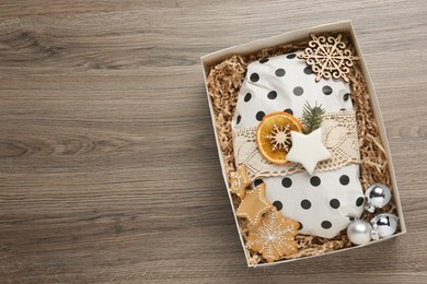 Photo of Wrapped Christmas Stollen and decoration in box on wooden table, top view. Space for text