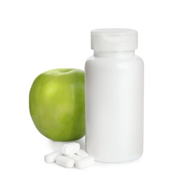 Bottle with vitamin pills and apple on white background