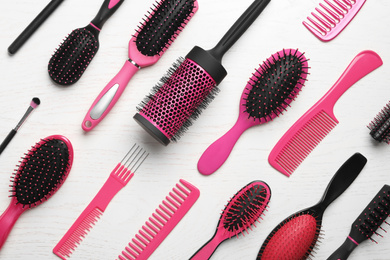 Photo of Different combs and brushes on white wooden background, closeup