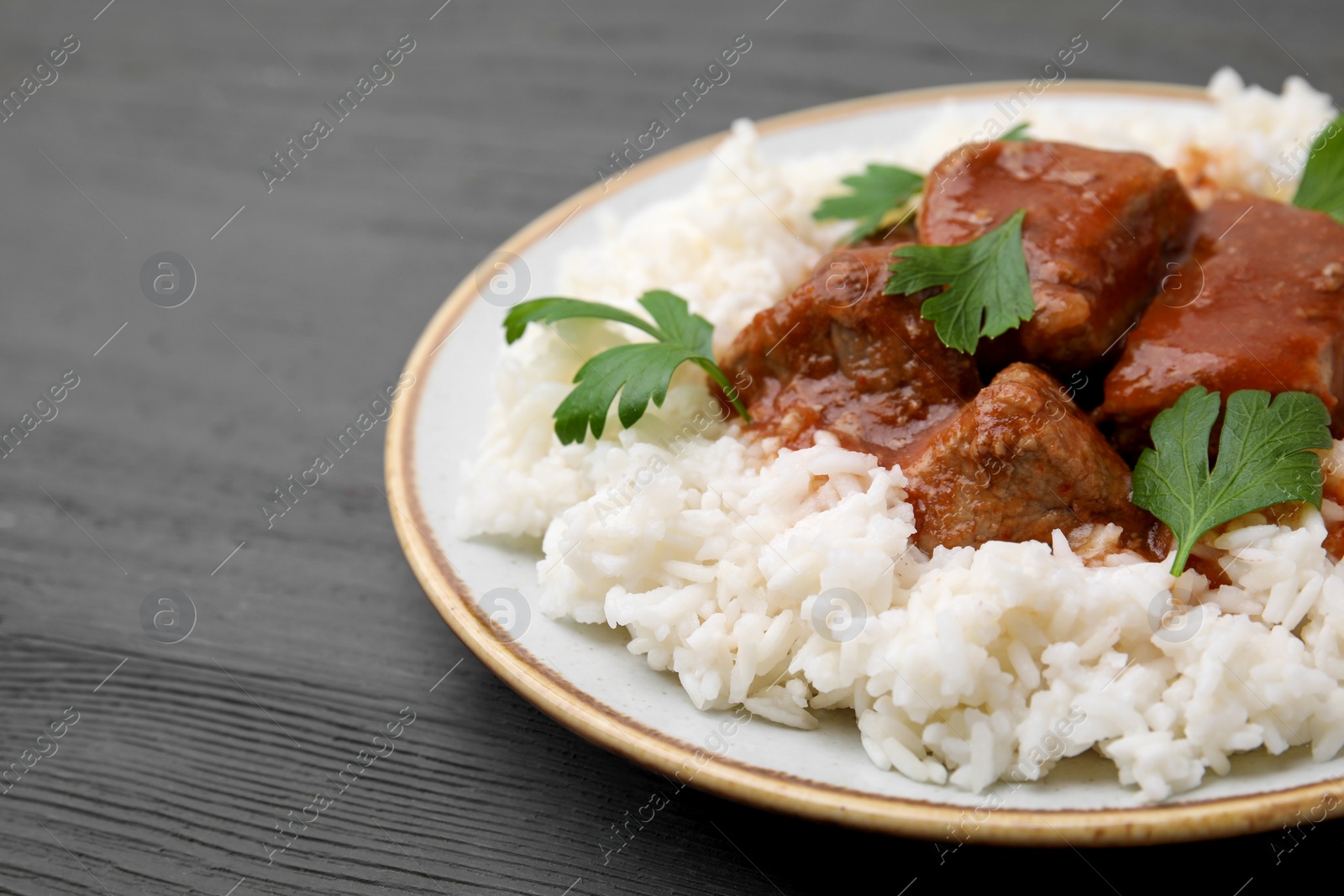 Photo of Delicious goulash with rice on grey wooden table, closeup