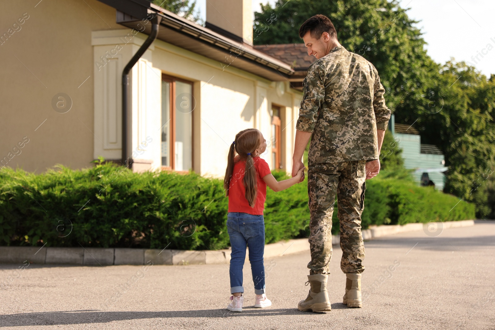 Photo of Father in military uniform with his little daughter outdoors