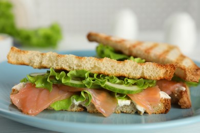 Photo of Tasty sandwiches with salmon on blue plate, closeup