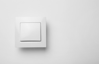 Photo of Modern plastic light switch on white background. Space for text